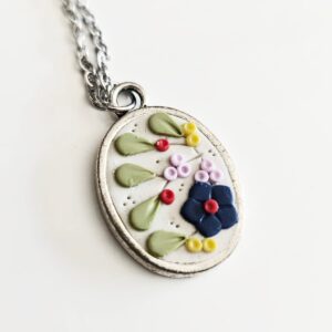Colgante original de arcilla polimérica con detalles florales y cadena de acero